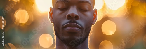 Man meditating peacefully with eyes closed against a warm bokeh background, banner © Tymofii