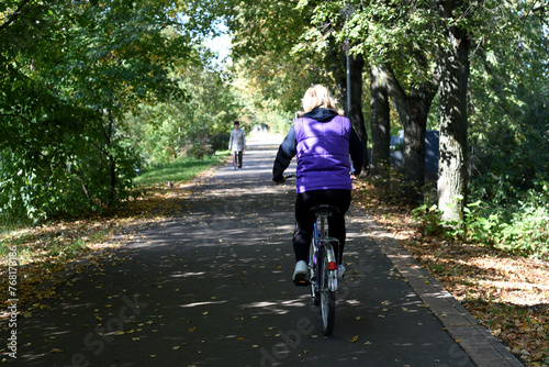 Wallpaper Mural Beginning of autumn. Sunny day. A cyclist is riding along a bike path in a park area, and a pedestrian is walking towards him. bokeh Torontodigital.ca