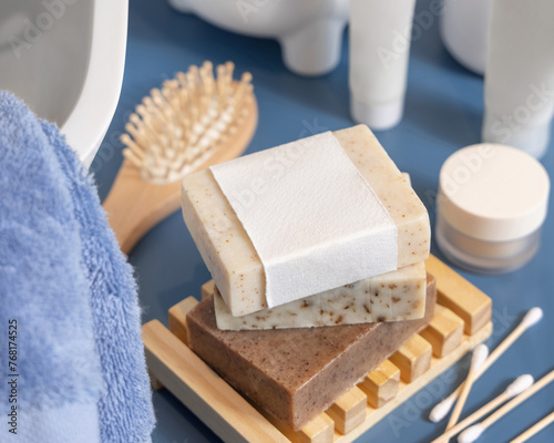 Soap bar with blank label near hygiene products on blue bathroom countertop close up, mockup