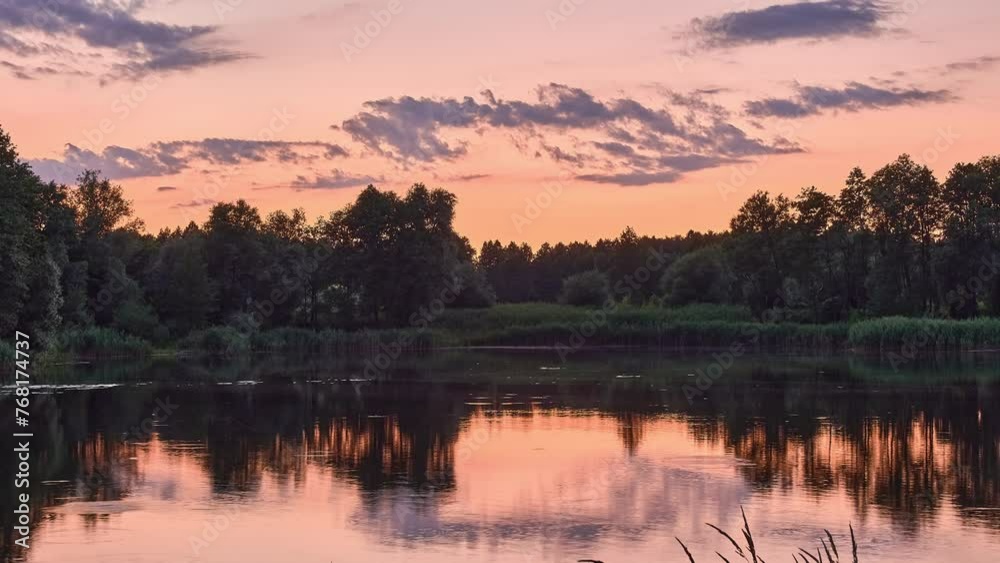 Evening sky with beautiful clouds and pink tint. Picturesque calm lake. On shore near water are green trees. Summer time. Evening sky with beautiful clouds and pink tint. Picturesque calm lake. On shore near water are green trees. Summer time.