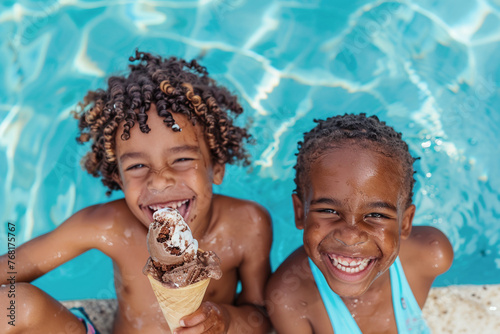 Retrato de dos niños negros dentro de una piscina en verano sonriendo y comiendo un helado