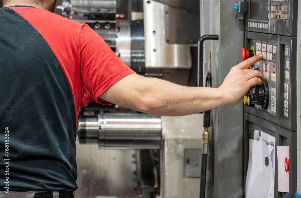Worker pressing buttons on CNC machine control board in factory. High quality photography.