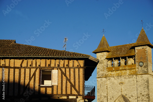 old stone church with two towers by a halftimbered house in a small french village photo
