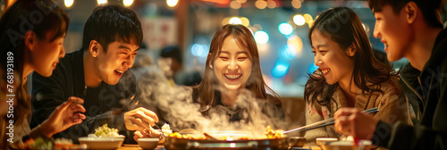 A group of Asian men and women are eating sukiyaki in a restaurant.