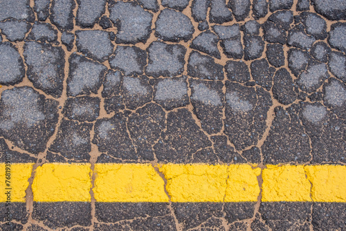 old cracked road with yellow line