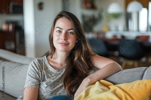 A Caucasian woman named Irene Montero sitting on top of a couch next to a yellow blanket. photo
