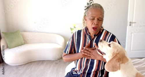 An African American senior woman is having chest pains or heart attack with her dog at home photo