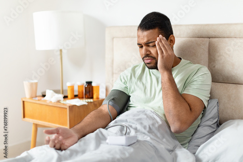 Man checking blood pressure in bed