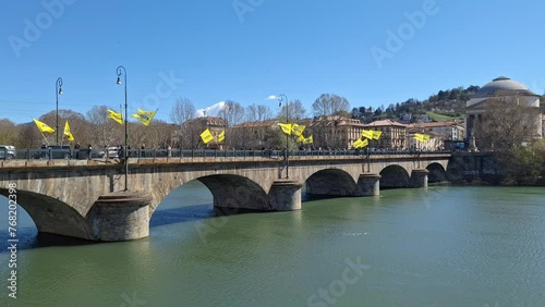 Turin, Piedmont, Italy - 03 24 2024: view of the Po river and the Umberto I bridge during a marathon with yellow flags waving in the wind photo