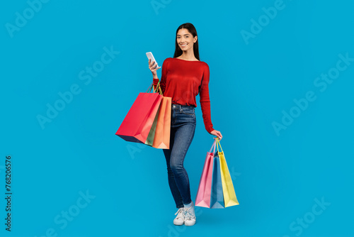 Woman Holding Shopping Bags And Cell Phone, Browsing Discount App