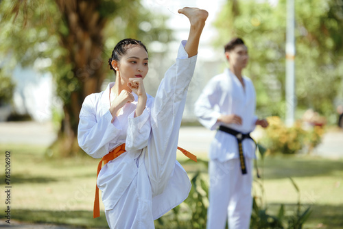 Taekwondo athlete doing high kick when training in park