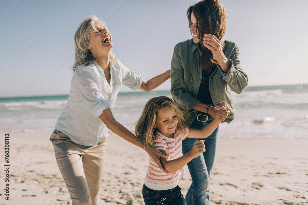 © Marko Geber - Happy family with grandmother, mother, and daughter playing on the beach © Marko Geber - Happy family with grandmother, mother, and daughter playing on the beach