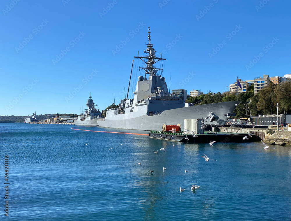 Military ships in the port of coastal city. Navy boats moored to a quay. Battleship in port. A country's fleet and marine defenses in a harbor.