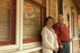A couple of older people are standing outside in front of a brick building