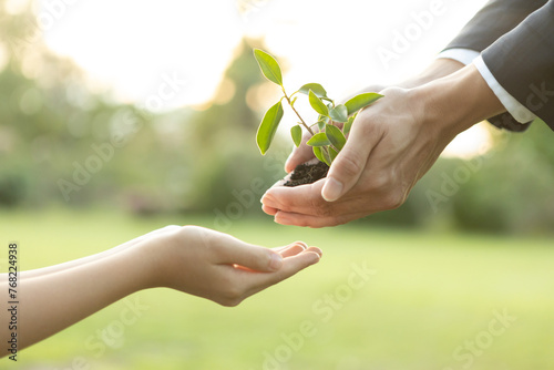 Businessman handing plant or sprout to young boy as eco company committed to corporate social responsible, reduce CO2 emission and embrace ESG principle for sustainable future.Gyre photo