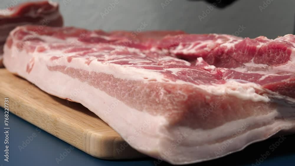 A man in black gloves cuts pork meat on a cutting board. Master class on cutting pork. A man in black gloves cuts pork meat on a cutting board. Master class on cutting pork.