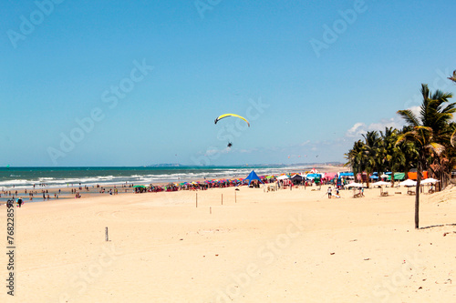 Fortaleza  Cear    Brazil  September 2022. Umbrellas  palm trees and paragliding at Future beach  Fortaleza  Cear    northeastern Brazil  on a sunny day with blue sky in the background.