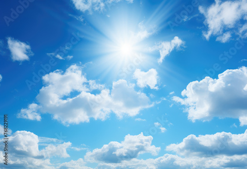 A blue sky with white clouds and the sun shining bright. Blue sky with clouds and sun reflection. The sun shines bright in the daytime in summer