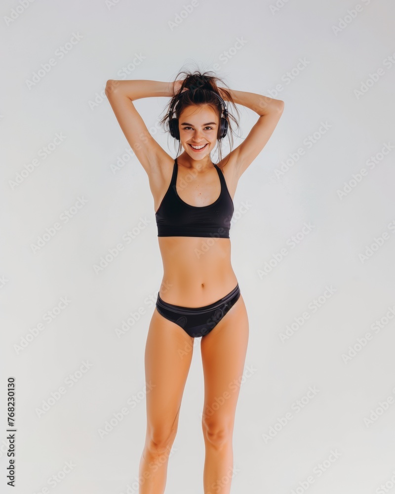 A young woman in sportswear and headphones smiles and listens to music. Active lifestyle. A young woman in sportswear and headphones smiles and listens to music. Active lifestyle.