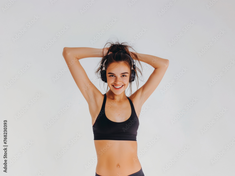 Fototapeta premium A young woman in sportswear and headphones smiles and listens to music. Active lifestyle.