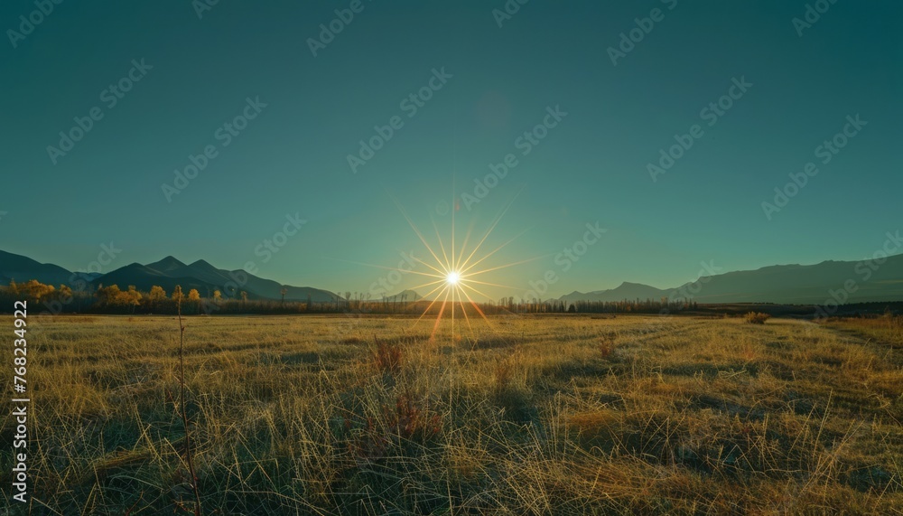 Sun Setting Over Field With Mountains