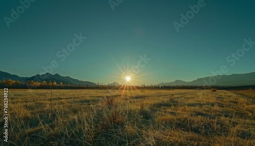 Sun Setting Over Field With Mountains