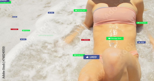 Image of social media notifications over caucasian woman sunbathing on beach