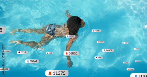 Image of social media notifications over biracial woman swimming in sunny pool