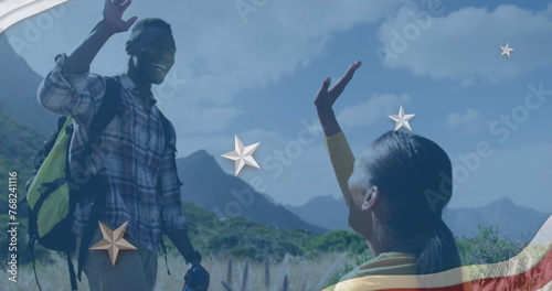 Image of american flag over african american couple high fiving in mountains