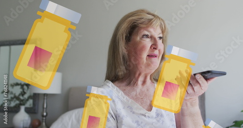 Image of box with pills icons over happy senior caucasian woman talking on smartphone