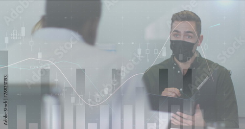 Image of statistics processing over business people wearing face masks in office