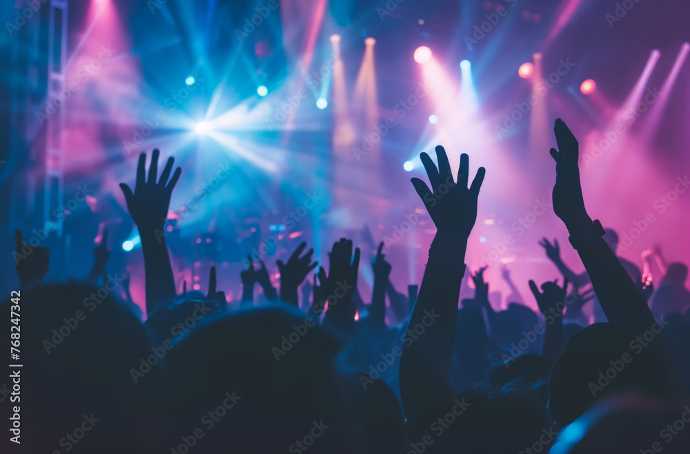 Concert with light effects and silhouettes of people rejoicing and raising their hands in the air