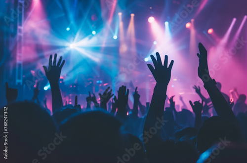 Concert with light effects and silhouettes of people rejoicing and raising their hands in the air