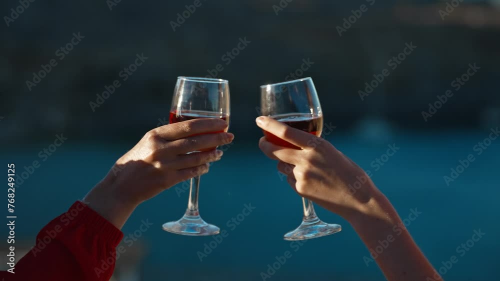 Women clink glasses of red wine against the backdrop of the sea. Women clink glasses of red wine against the backdrop of the sea.