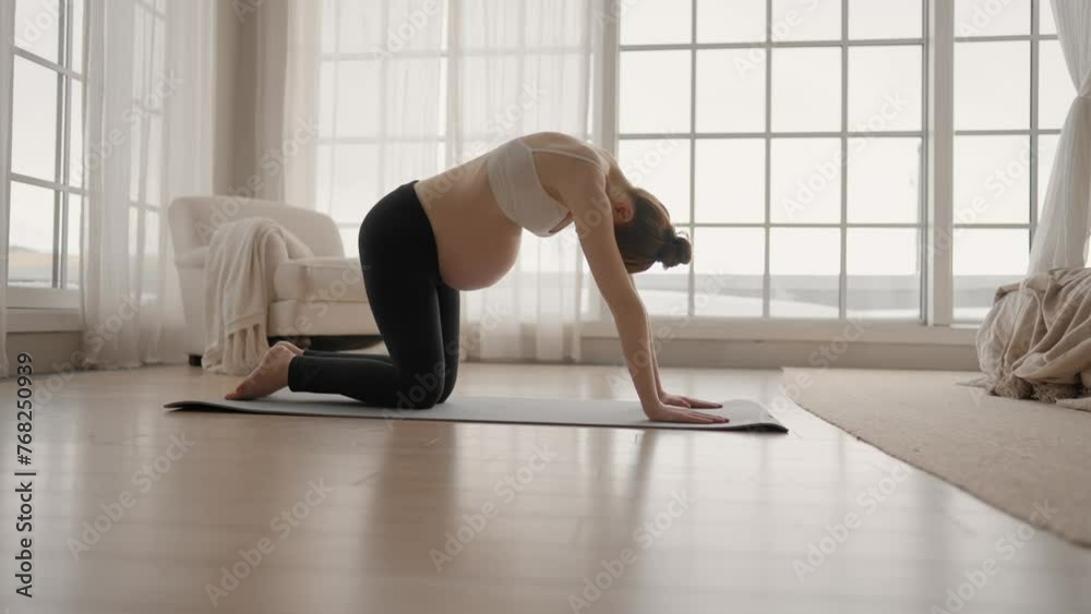 Young pregnant woman doing yoga at home. Pregnant girl with big belly practice yoga, does stretching, deep breath after wake up, meditation. Healthy pregnant yoga, prenatal fitness balance concept.