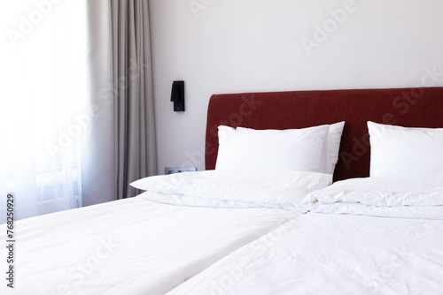 Clean Bedding sheets and pillow on natural wall room background. White bedding and pillow in hotel room. White pillows on empty bed. © KatrinaEra