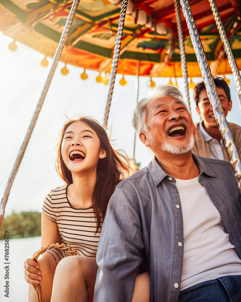 Grandfather of Asian origin enjoys fun with teenage granddaughter at fair, creating generational joy