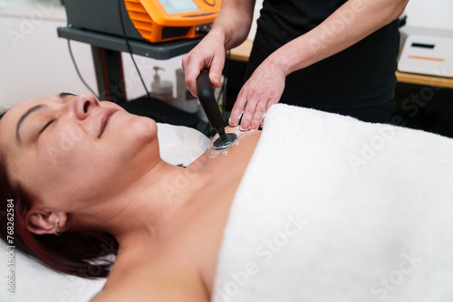 Patient relaxes during a soothing electrotherapy treatment on neck. photo