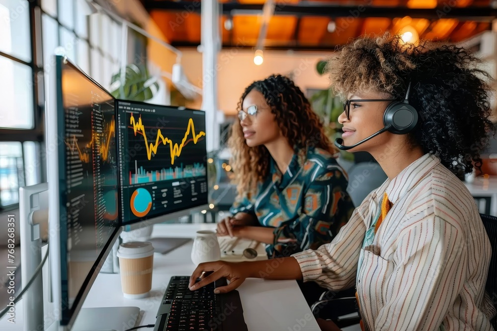 Two people engaged in data analysis using multiple computer monitors for business or finance Two people engaged in data analysis using multiple computer monitors for business or finance