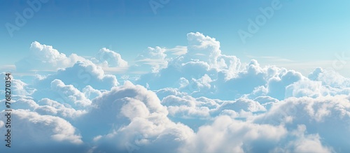 The vast expanse of the sky is painted with a beautiful shade of blue, adorned with fluffy white cumulus clouds, creating a picturesque natural landscape against the horizon
