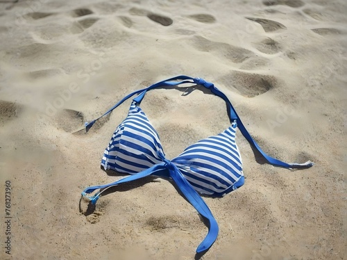 Sandy beach on a bright sunny day with a bikini trown away on the sand photo