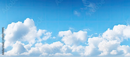 Fluffy white clouds drift peacefully in the blue sky hanging over the calm water below in a serene natural scene