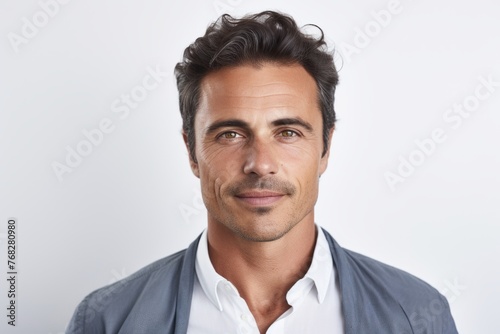 Portrait of handsome young man looking at camera and smiling while standing against grey background