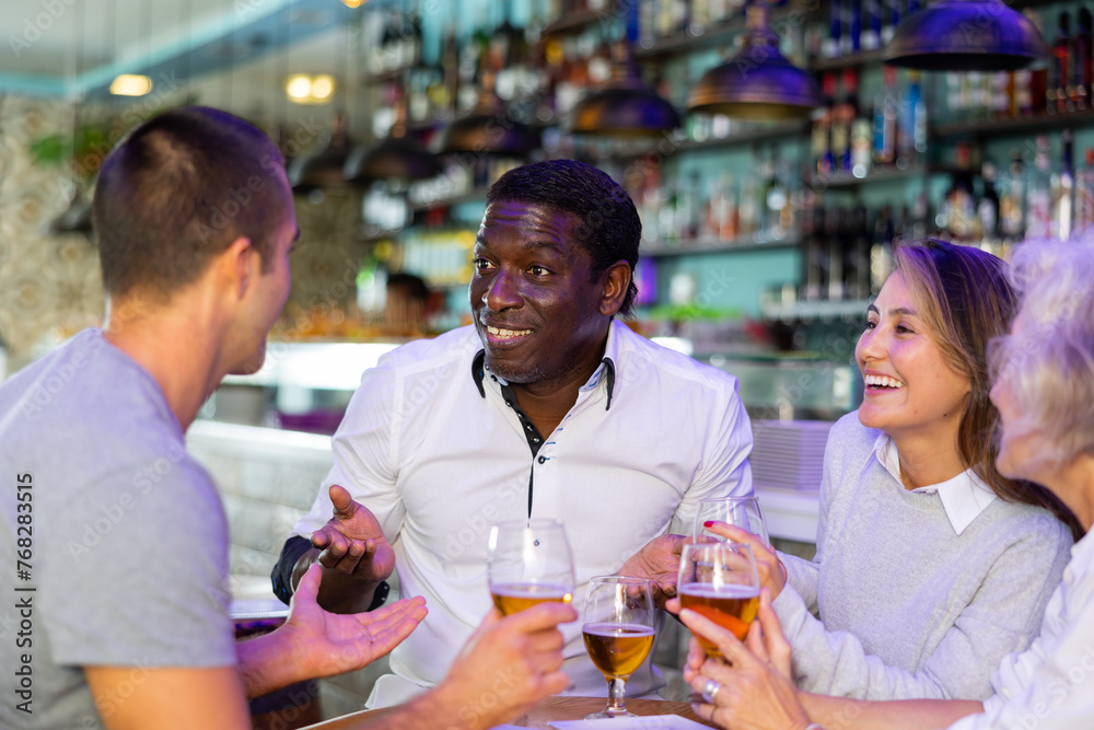 View on the happy diverse group laugh at a bar with beer