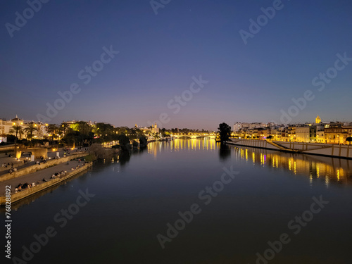 View of the Guadalquivir River in the night illuminations at sunset in Seville, Andalusia, Spain © Ирина Селина