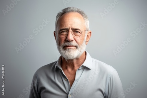 Portrait of a handsome senior man in glasses on grey background.