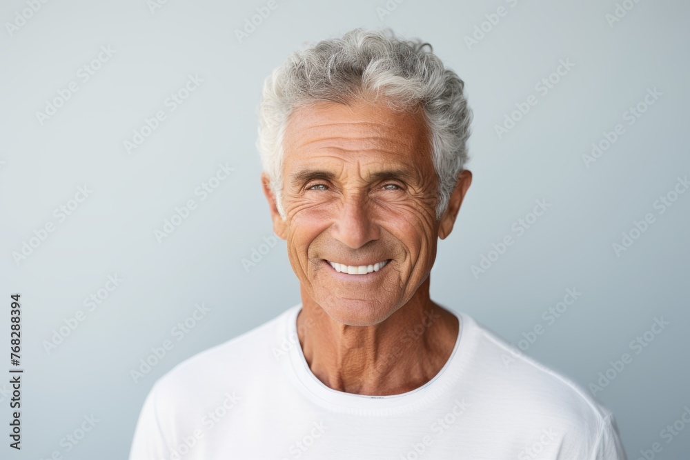 Portrait of a smiling senior man looking at camera against grey background Portrait of a smiling senior man looking at camera against grey background