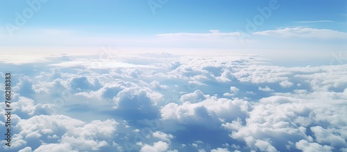 Gazing at the cumulus clouds from the airplane window, against the electric blue sky, showcases a stunning natural landscape and horizon
