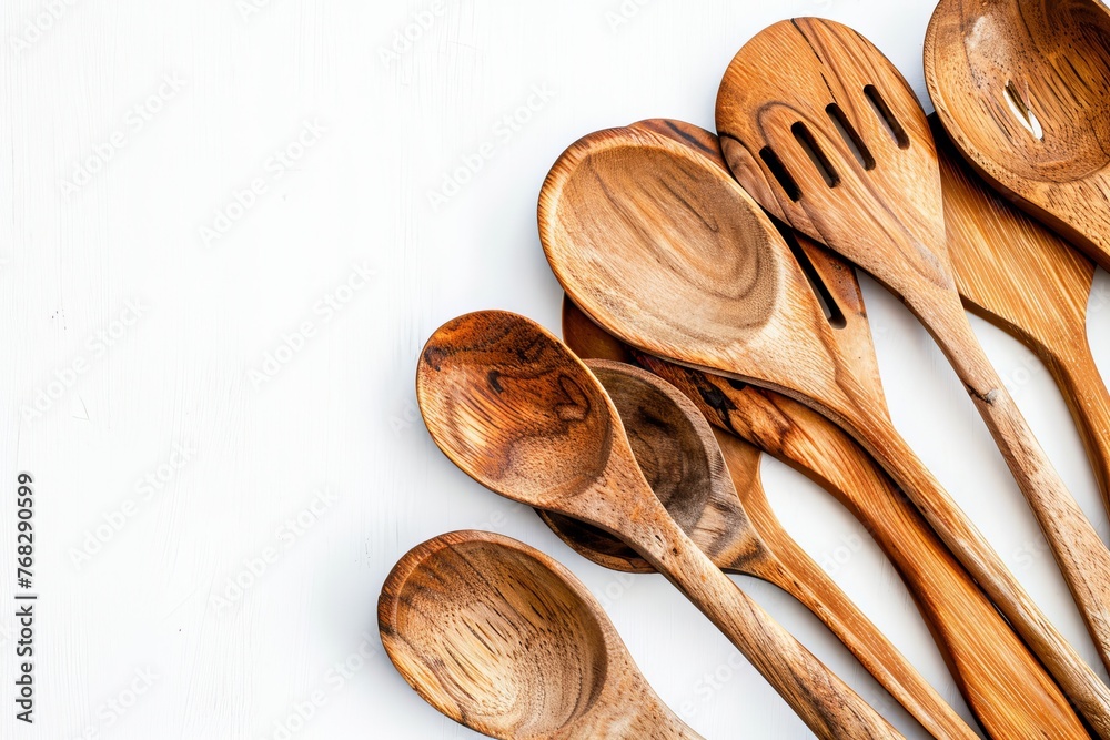 Flat lay of assorted wooden kitchen utensils including spoons of different sizes and shapes organized neatly on a white backdrop Flat lay of assorted wooden kitchen utensils including spoons of different sizes and shapes organized neatly on a white backdrop