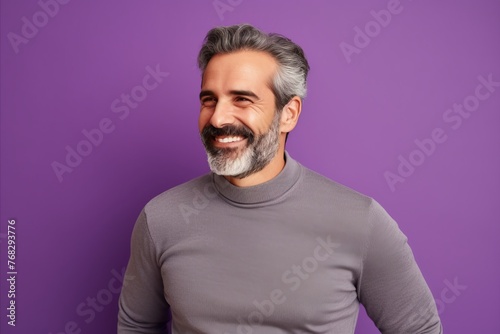 Portrait of happy mature man with grey hair and beard, isolated over purple background